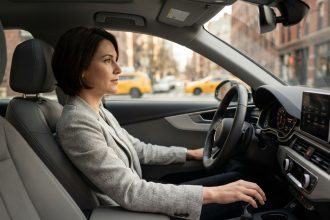 Conductrice au volant d'une voiture automatique moderne, main sur le sélecteur de vitesse, en conduite urbaine